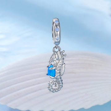 Silver seahorse pendant with blue gemstone on a light blue background