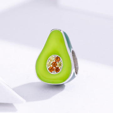 Avocado-shaped jewelry charm with gemstones on a light background