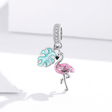 Jewelry charm with pink flamingo and blue leaf design on a white background