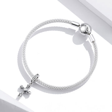 Silver bracelet with a cross charm on a white background