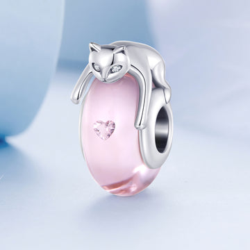 Pink cat-shaped charm with a silver outline on a light blue background