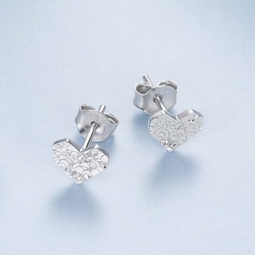 Silver heart-shaped earrings on a light blue background