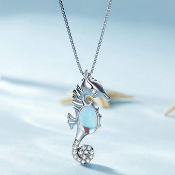 Seahorse-shaped necklace with a blue gemstone on a light blue background