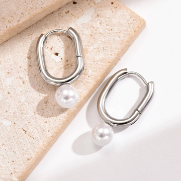 Silver hoop earrings with pearls on a textured surface