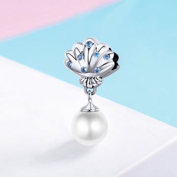 Pearl charm with shell design and blue stones on a colorful background