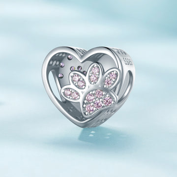 Heart-shaped charm with paw prints and pink stones on a light blue background