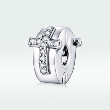 Silver cross charm with clear stones on a white background