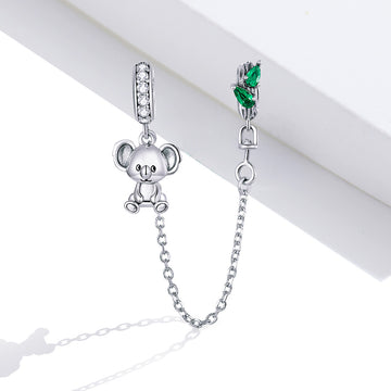 Silver teddy bear charm with a chain and green gemstone on a white background