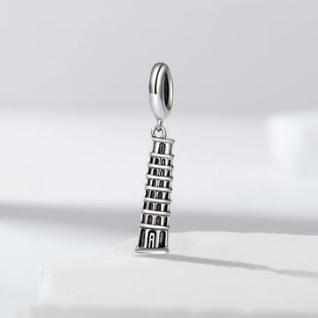 Silver charm shaped like the Leaning Tower of Pisa on a light gray background