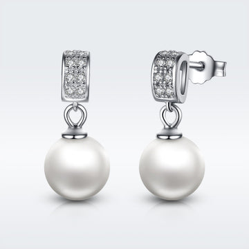Pearl earrings with diamond accents on a light gray background