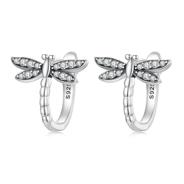 Silver dragonfly-shaped earrings with clear gemstones on a white background