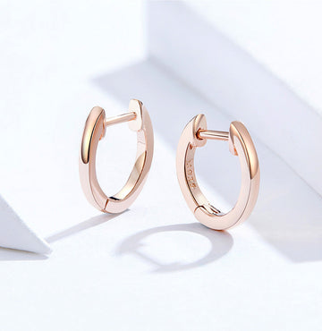 Rose gold hoop earrings on a light background