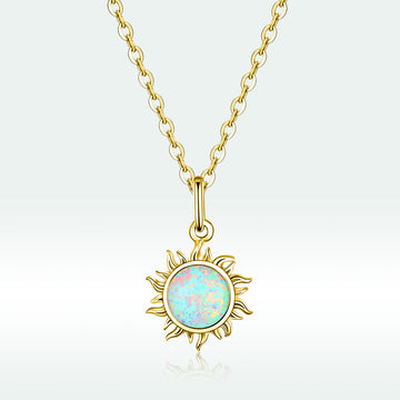 Gold necklace with a sun-shaped pendant featuring an opal stone on a light gray background