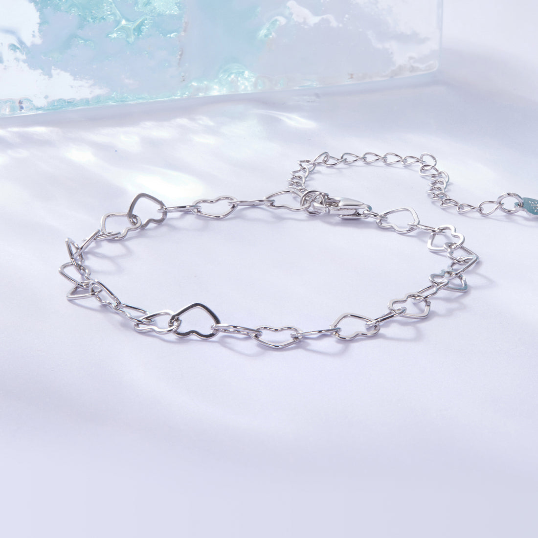 Silver chain bracelet on a light blue and white gradient background
