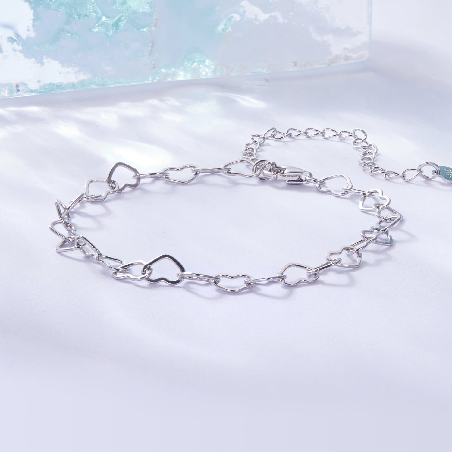 Silver chain bracelet on a light blue and white gradient background