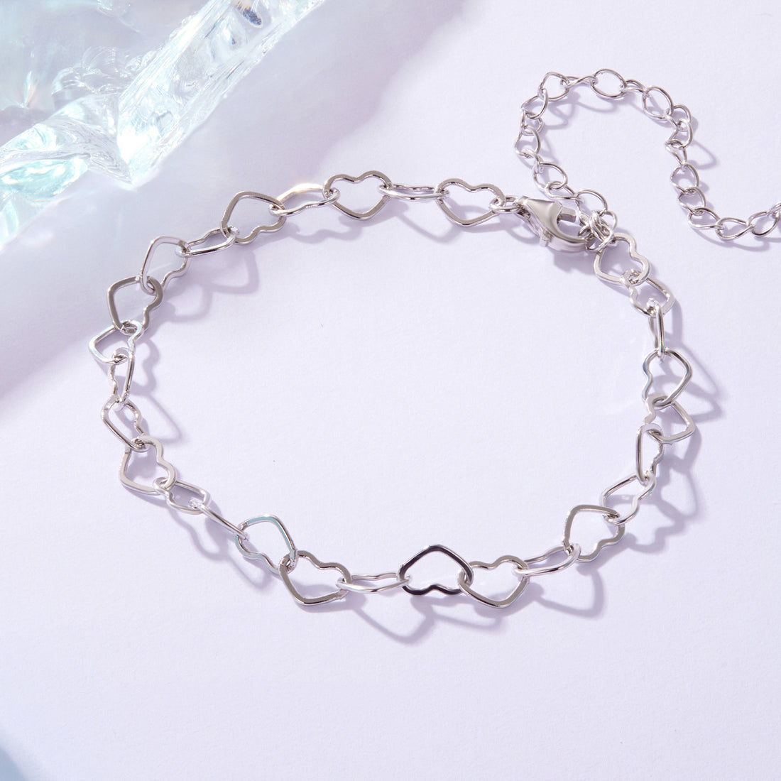Silver chain bracelet on a light blue and white gradient background