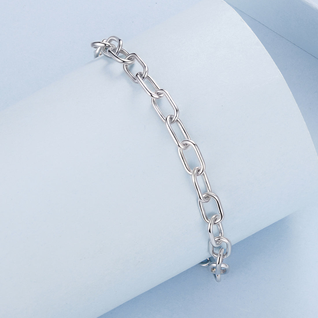Silver chain bracelet on a light blue geometric background