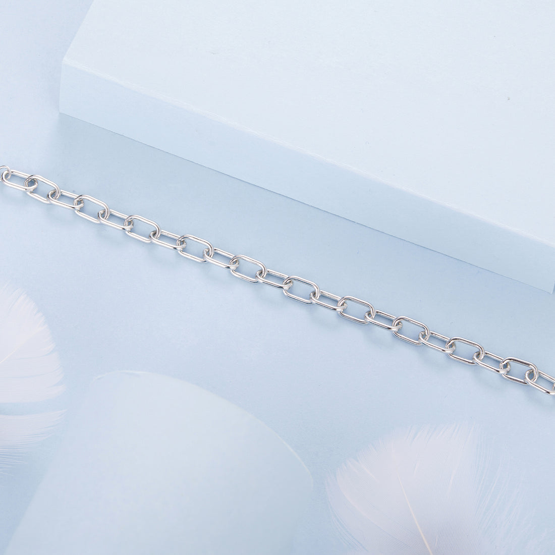 Silver chain bracelet on a light blue geometric background