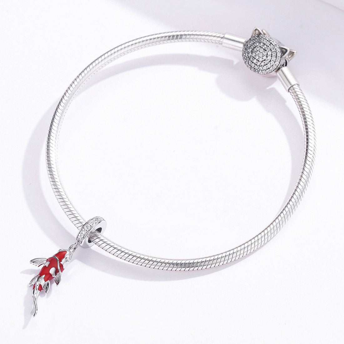 Red fish-shaped pendant with silver accents on a white background