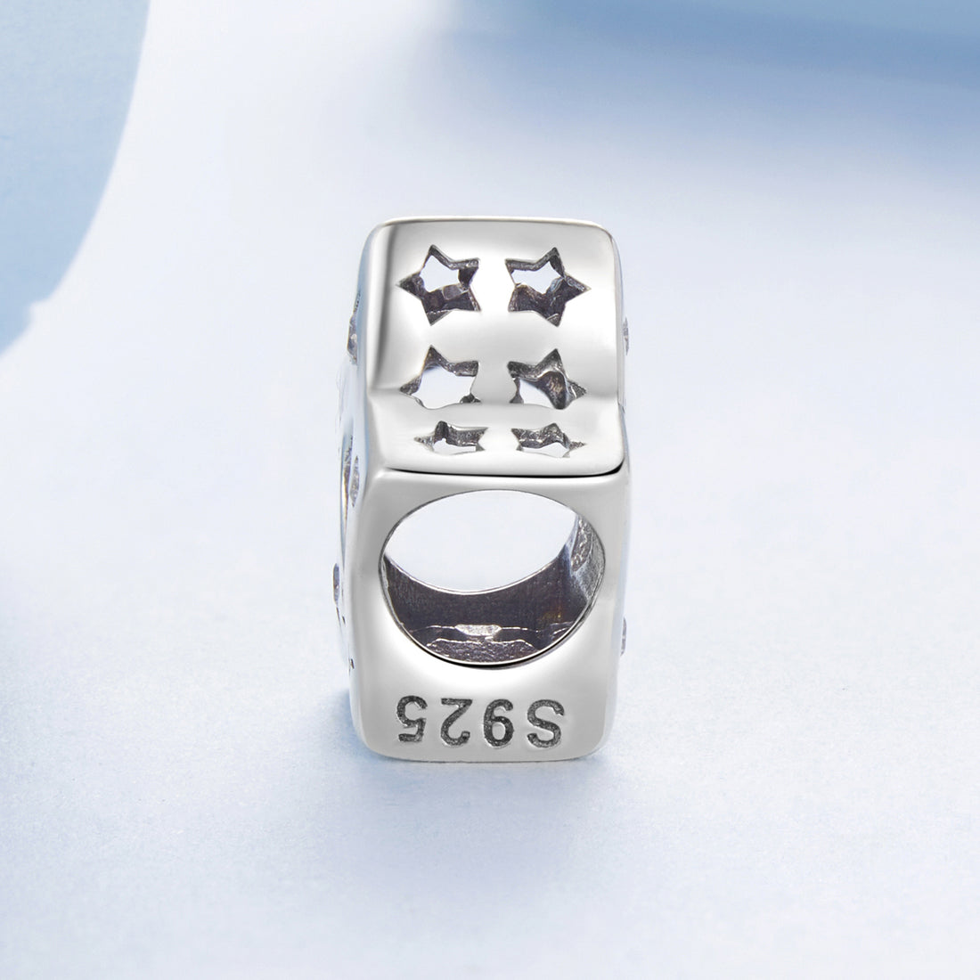 Silver star-shaped charm with 'lucky star' engraving on a light blue background