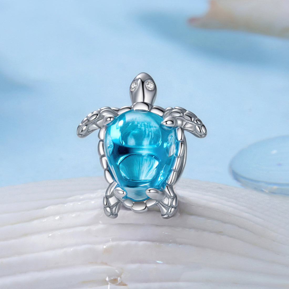 Silver turtle pendant with a blue gemstone on a beach setting