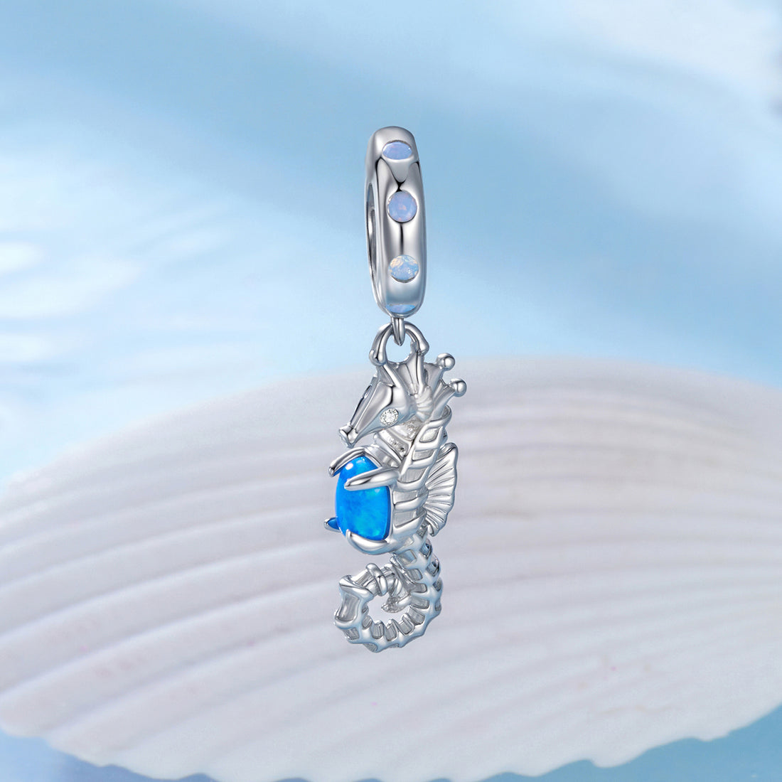 Silver seahorse pendant with blue gemstone on a light blue background