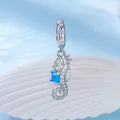 Silver seahorse pendant with blue gemstone on a light blue background