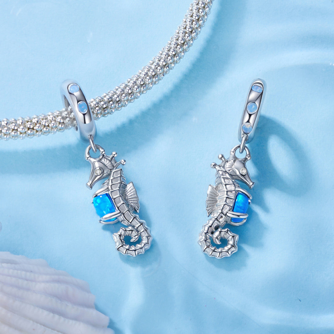 Silver seahorse pendant with blue gemstone on a light blue background