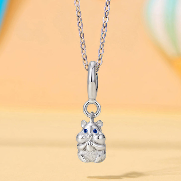 Silver cat-shaped pendant on a chain against a blurred background