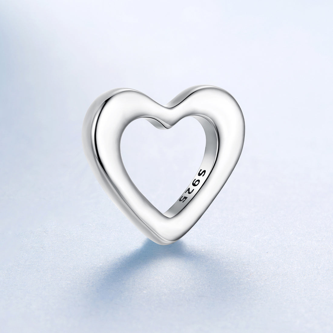 Silver heart-shaped pendant with '925' stamp on a light blue background