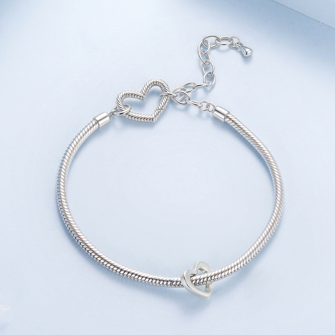 Silver heart-shaped pendant with '925' stamp on a light blue background