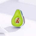Avocado-shaped jewelry charm with gemstones on a light background