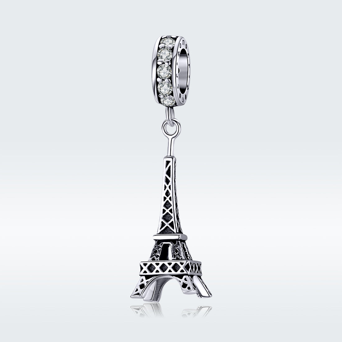 Silver Eiffel Tower charm with clear gemstones on a white background