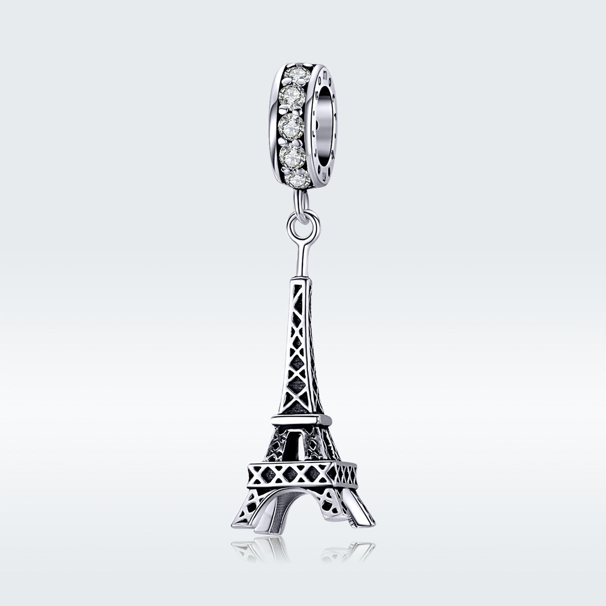 Silver Eiffel Tower charm with clear gemstones on a white background