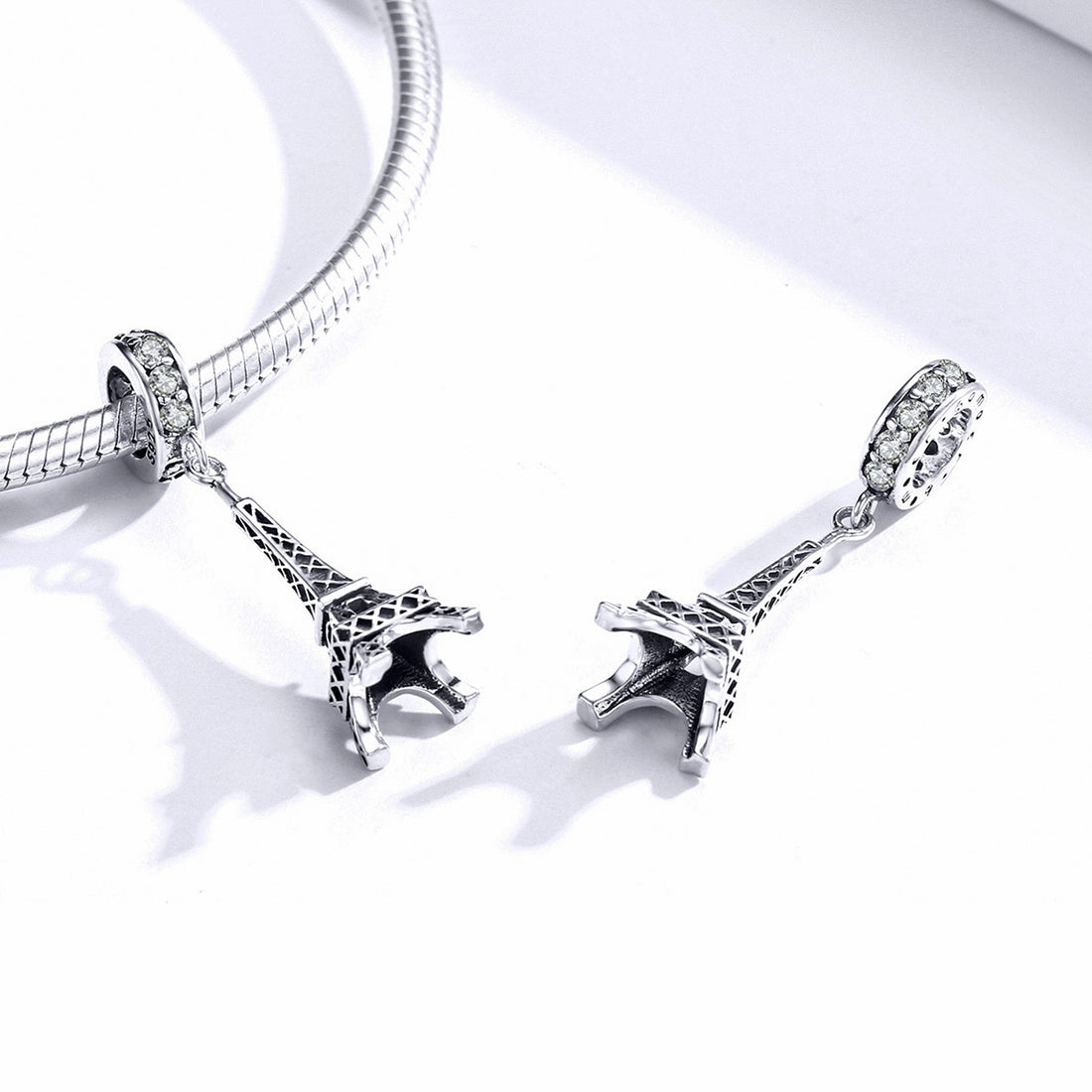 Silver Eiffel Tower charm with clear gemstones on a white background