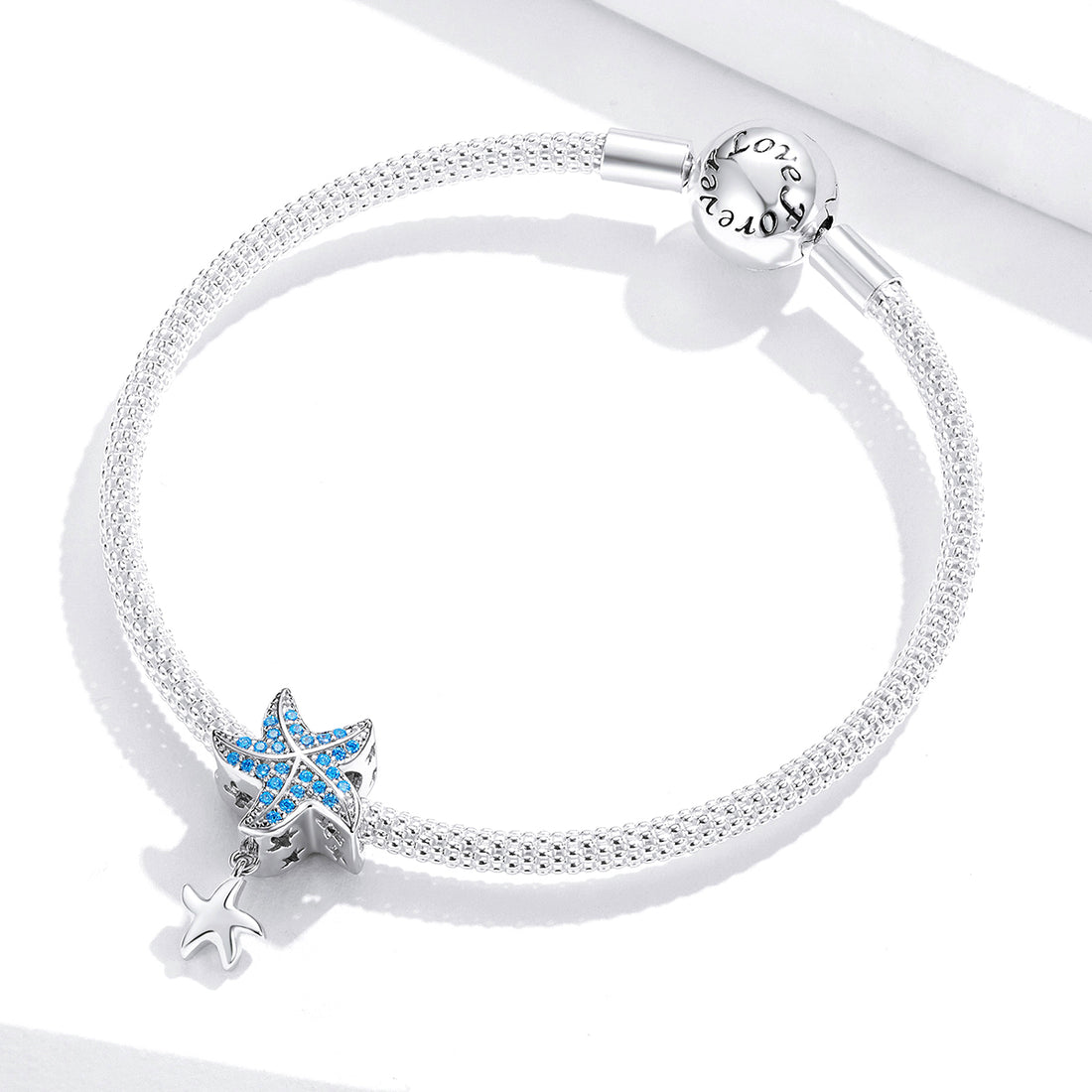Starfish-shaped charm with blue gemstones on a light gray background