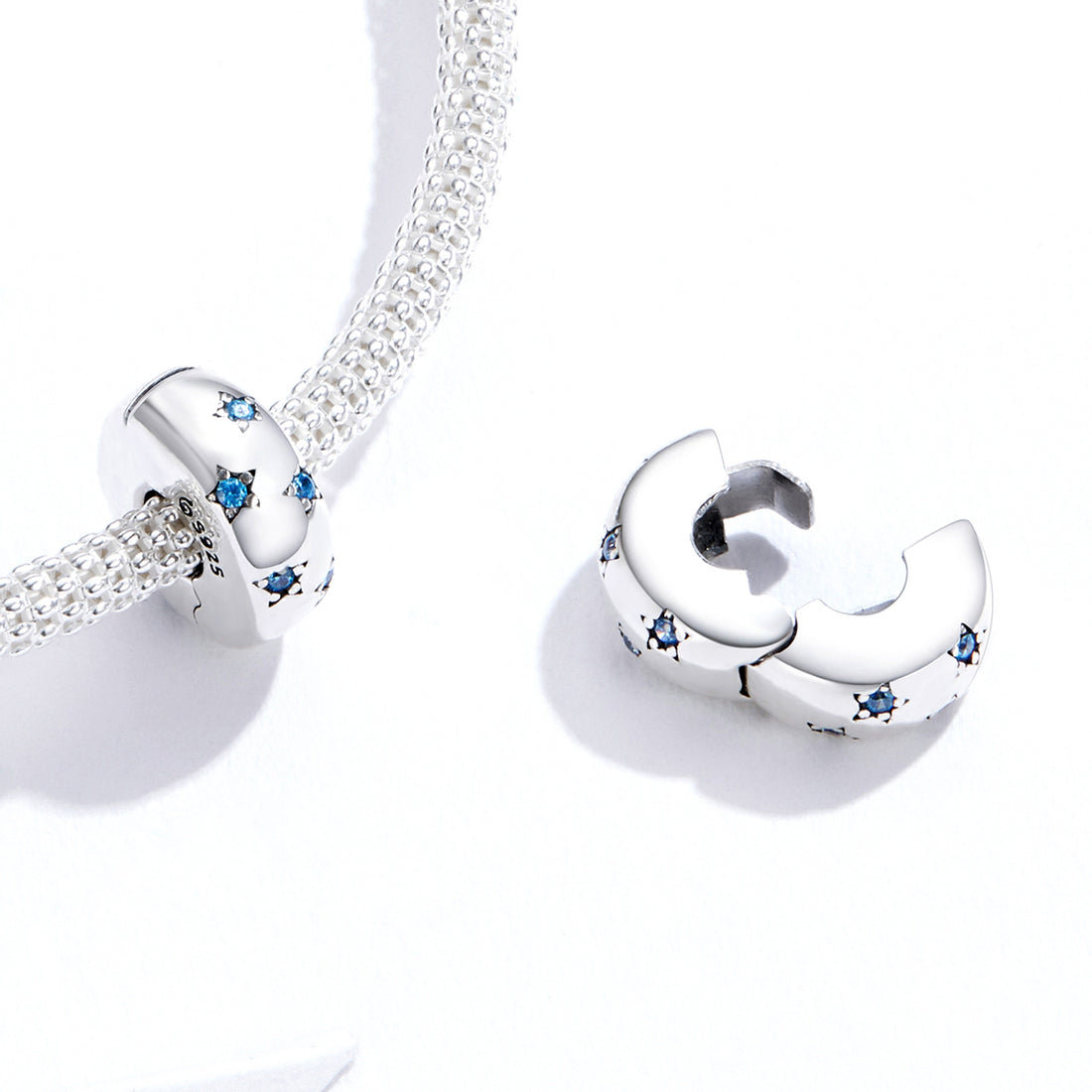 Silver charm with blue gemstones on a white background