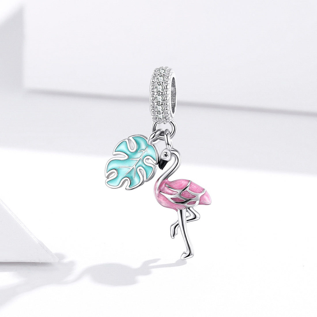 Jewelry charm with pink flamingo and blue leaf design on a white background