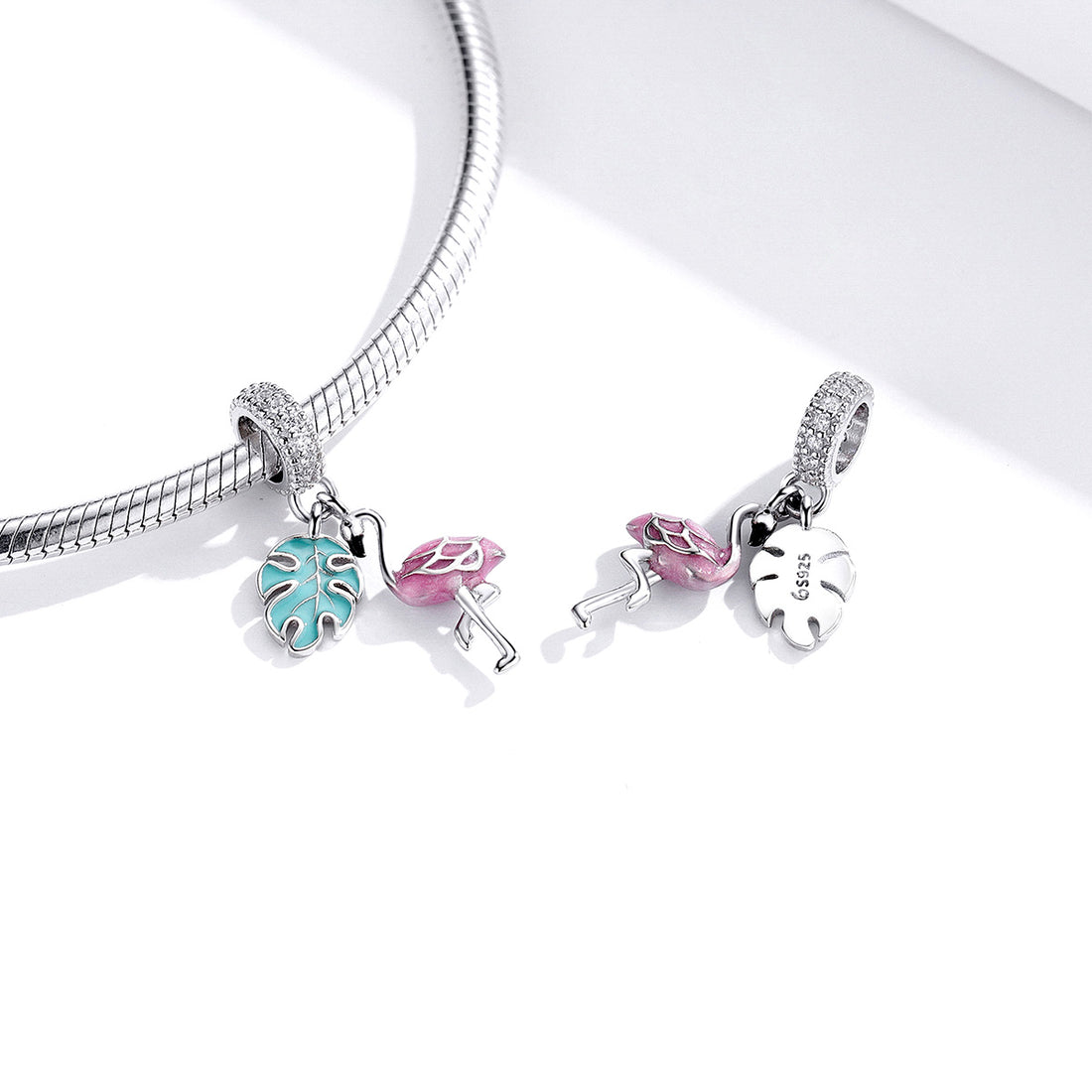Jewelry charm with pink flamingo and blue leaf design on a white background