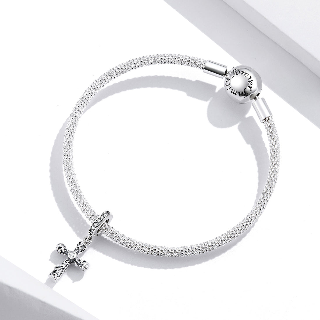 Silver bracelet with a cross charm on a white background