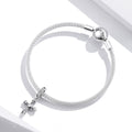 Silver bracelet with a cross charm on a white background
