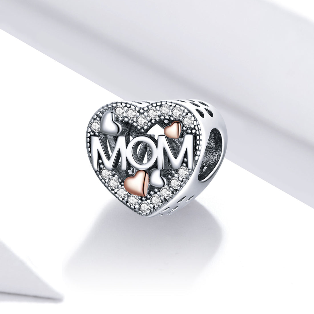 Heart-shaped silver charm with 'MOM' and heart designs on a white background