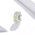 Silver ring with white and yellow flower designs on a white background