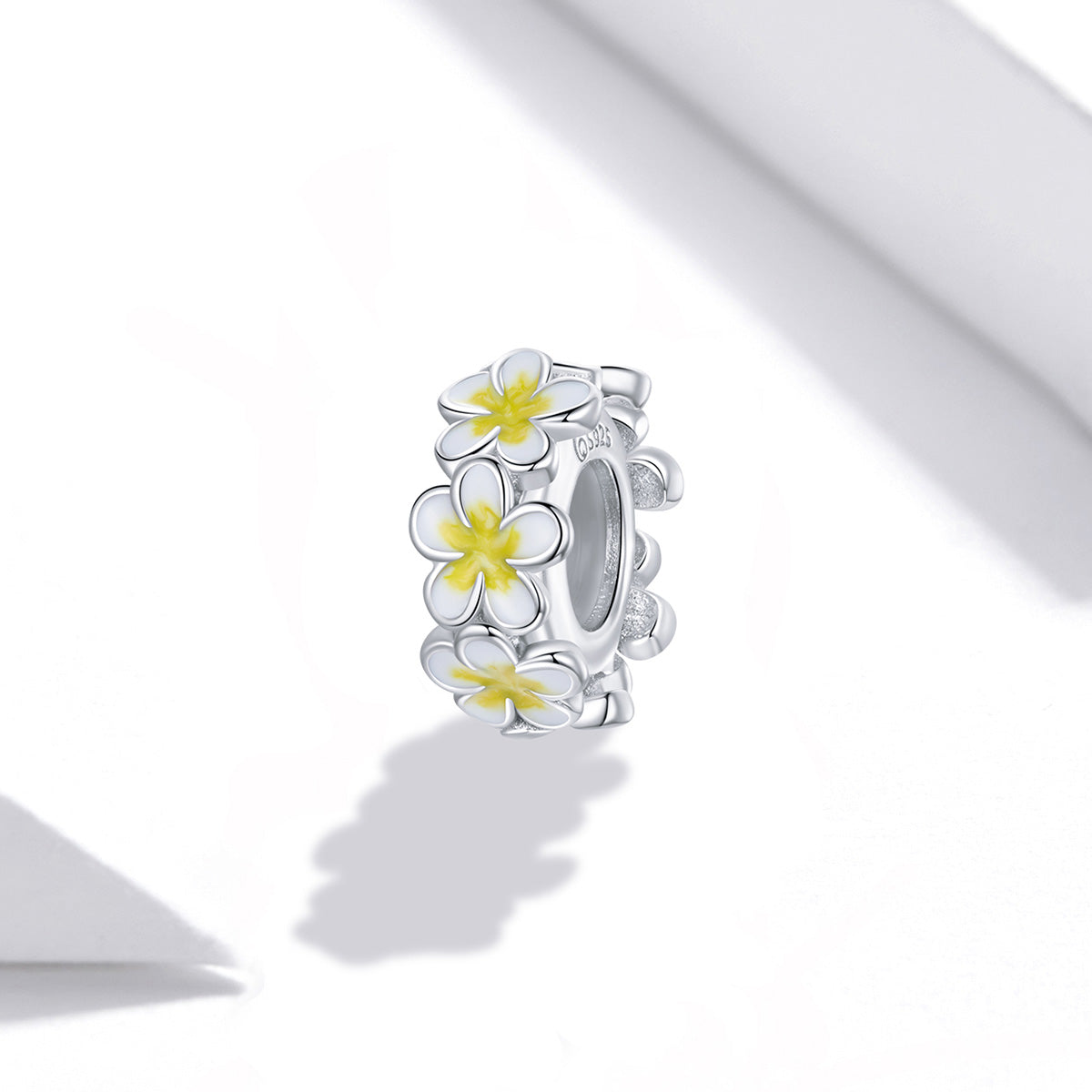 Silver ring with white and yellow flower designs on a white background