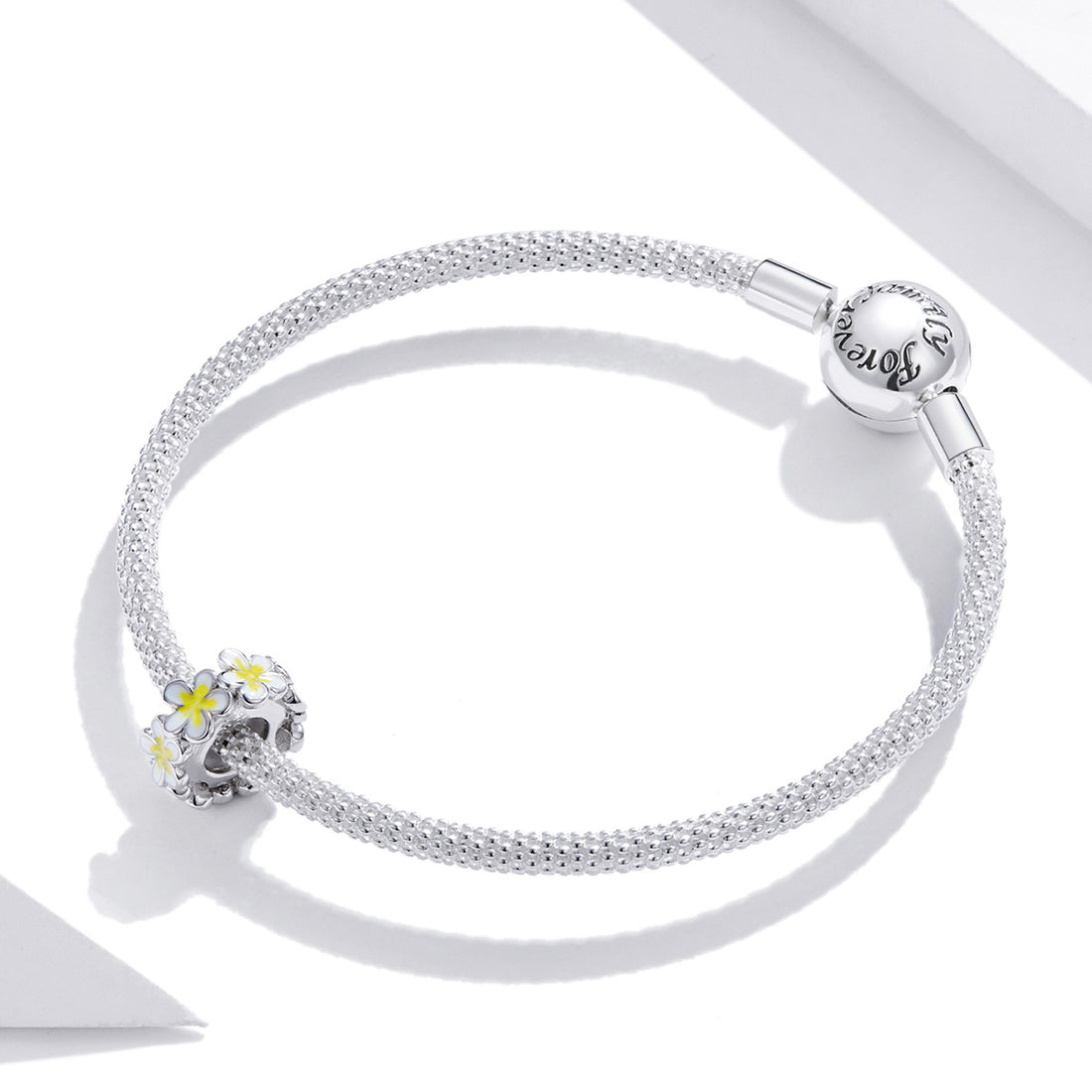 Silver ring with white and yellow flower designs on a white background