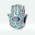 Silver and turquoise Hamsa hand charm with an eye design on a white background