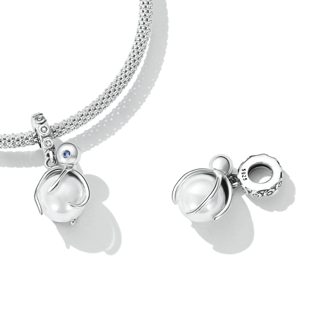Silver charm with a blue gemstone on a white background