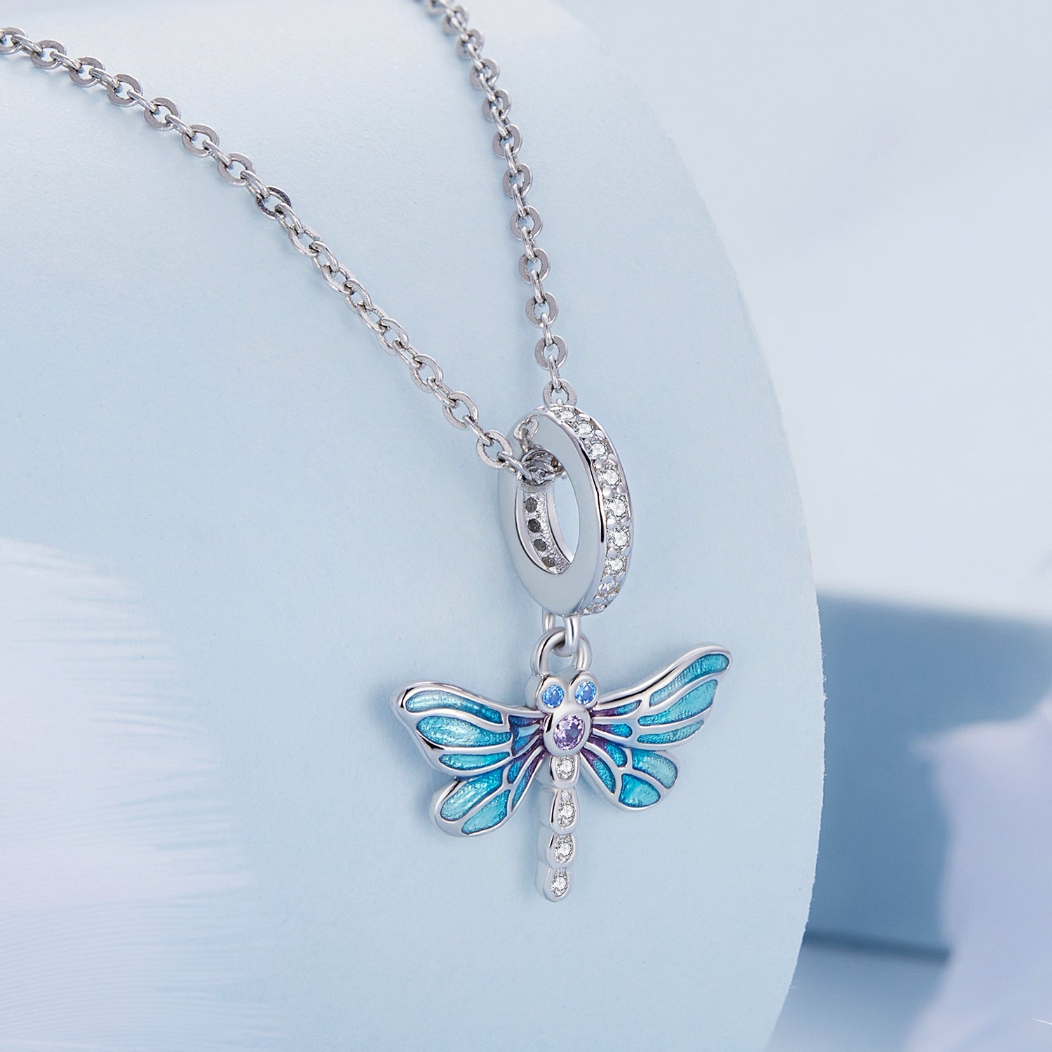Butterfly-shaped pendant on a chain against a light blue background