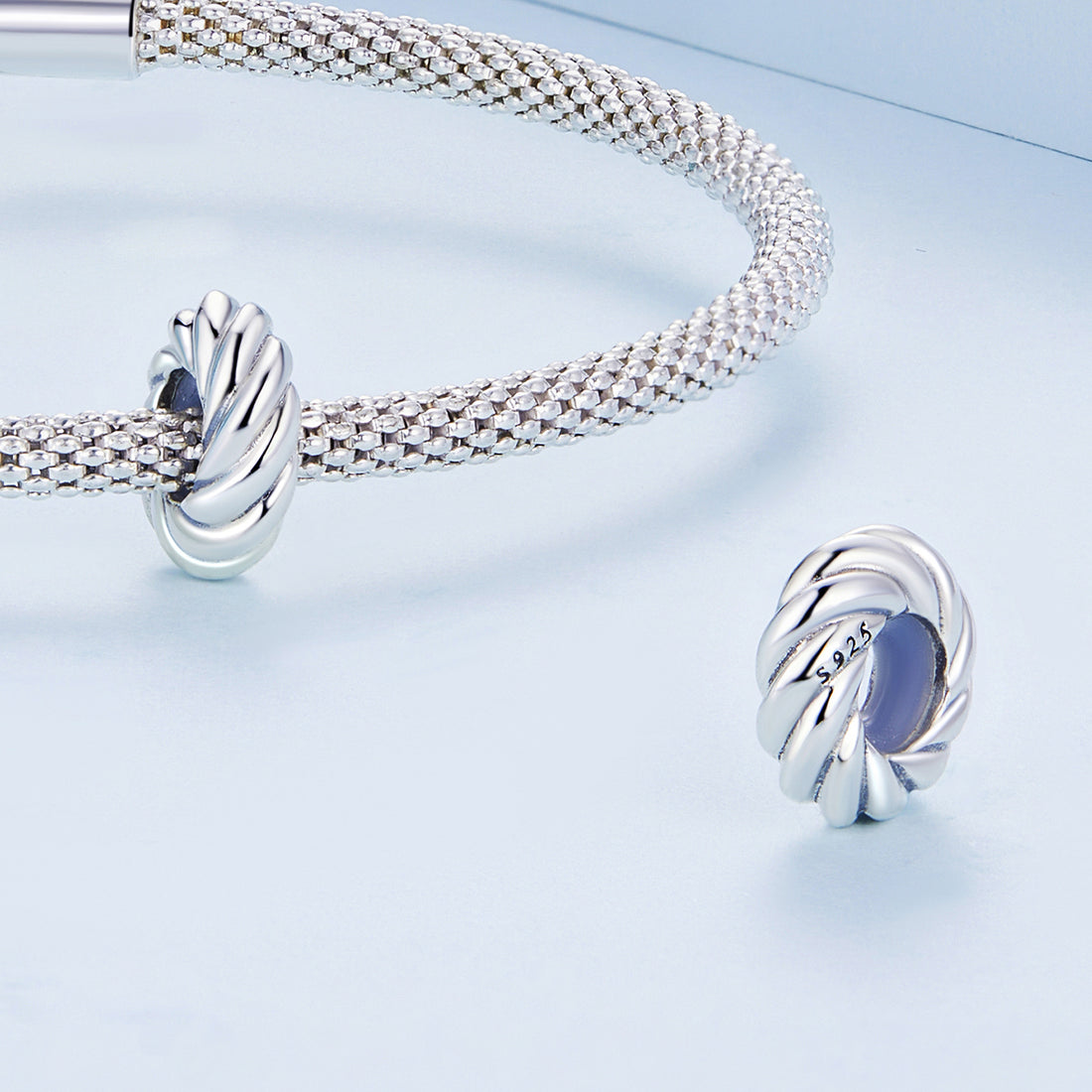 Silver bracelet and earrings on a light blue background