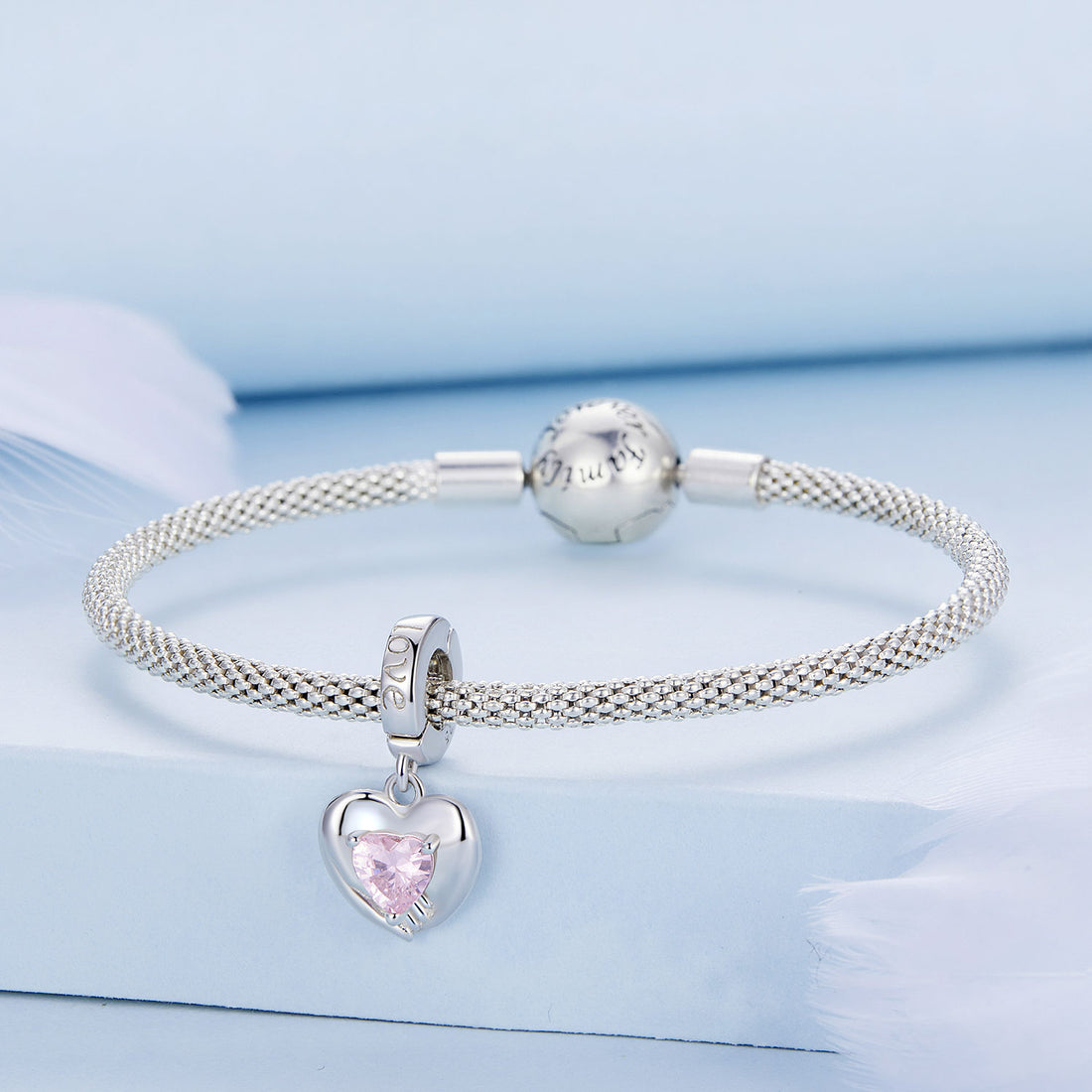 Silver heart-shaped charm with a pink gemstone on a white background